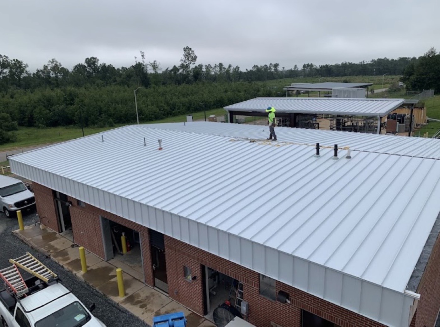 Worker on a finished standing-seam metal roof on a commercial building