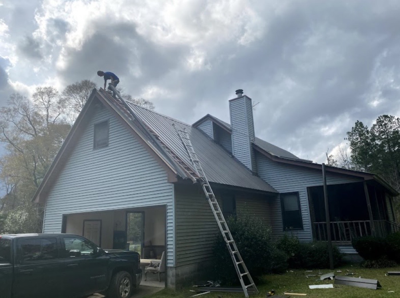 Crew member working on a metal roof install from a ladder