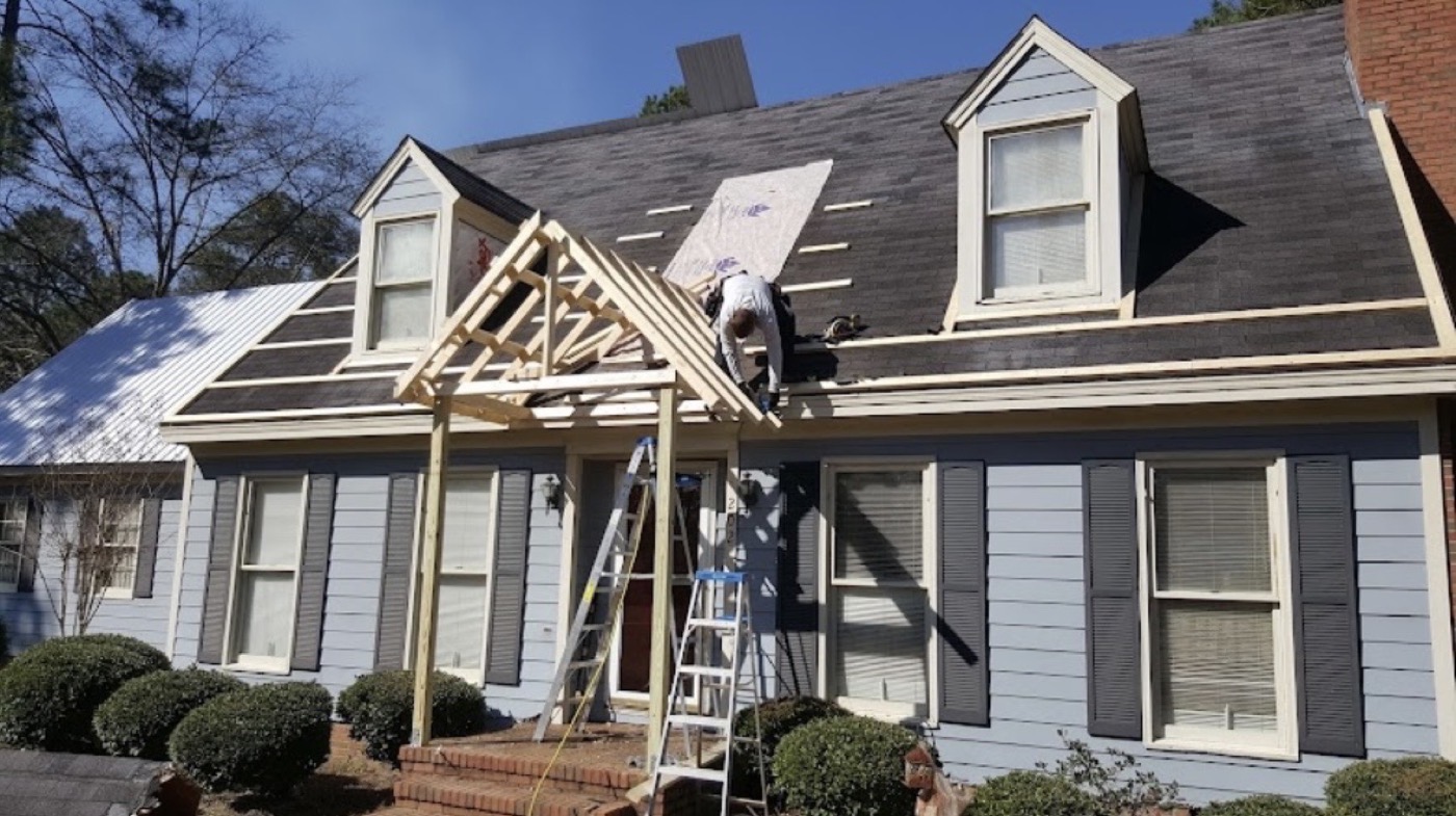 Crew member framing a new porch roof structure over a home's front entrance